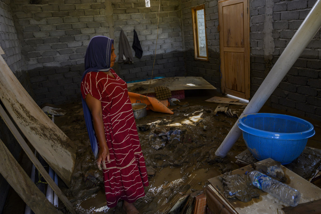 Warga mengumpulkan barang-barang dari rumahnya yang digenangi lumpur banjir akibat luapan sungai di Desa Lumbudolo, Kecamatan Banawa Tengah, Kabupaten Donggala, Sulawesi Tengah.