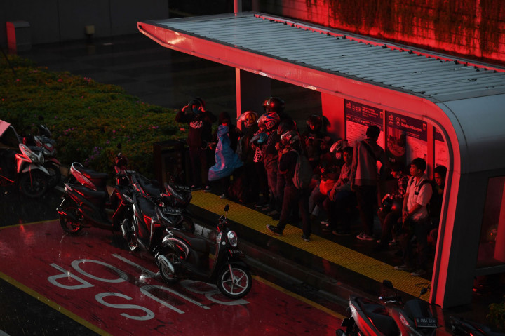 Sejumlah warga berteduh di sebuah halte saat turun hujan di Jalan Jenderal Sudirman, Jakarta.