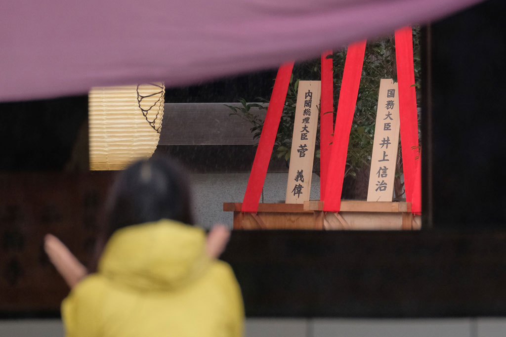 Sebuah plakat kayu (latar belakang, kanan) yang menunjukkan nama Perdana Menteri Jepang Yoshihide Suga terlihat dengan pohon 'masakaki' yang dikirimnya sebagai persembahan ke Kuil Yasukuni yang kontroversial di Tokyo, pada Sabtu, 17 Oktober 2020.