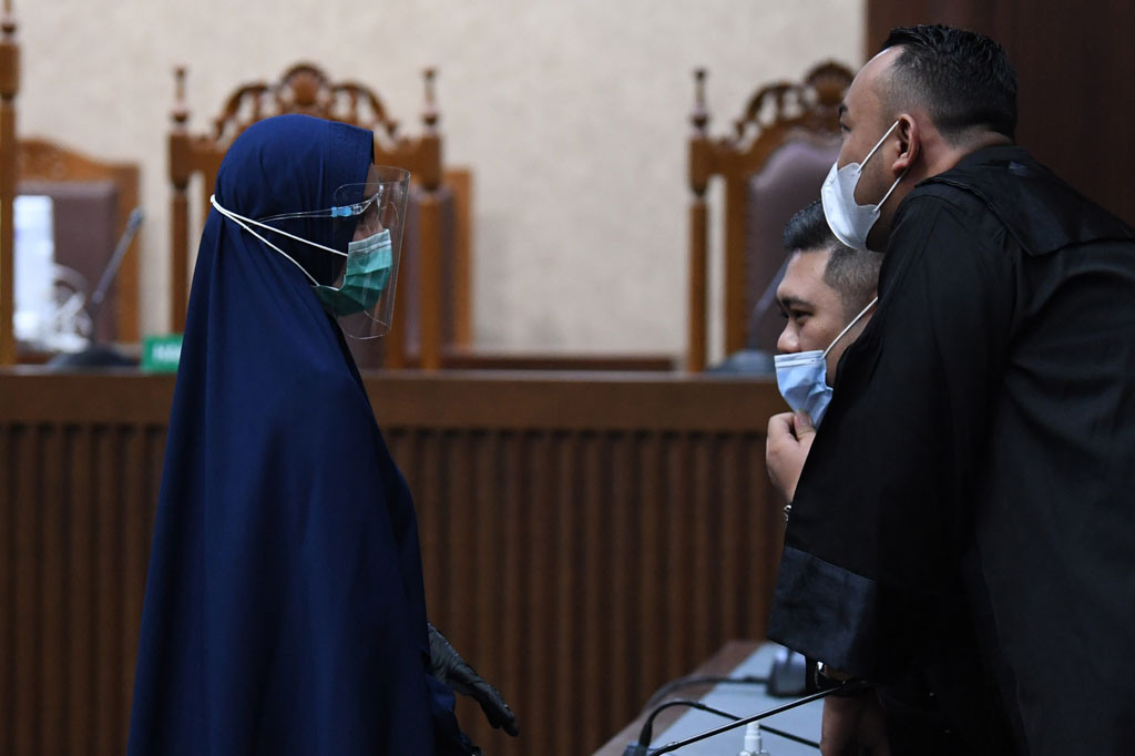 Pinangki tampak mengenakan busana muslim syar'i berwarna biru dongker dengan hijab warna senada. Dia juga mengenakan sarung tangan berwarna hitam, masker berwarna biru, serta face shield.