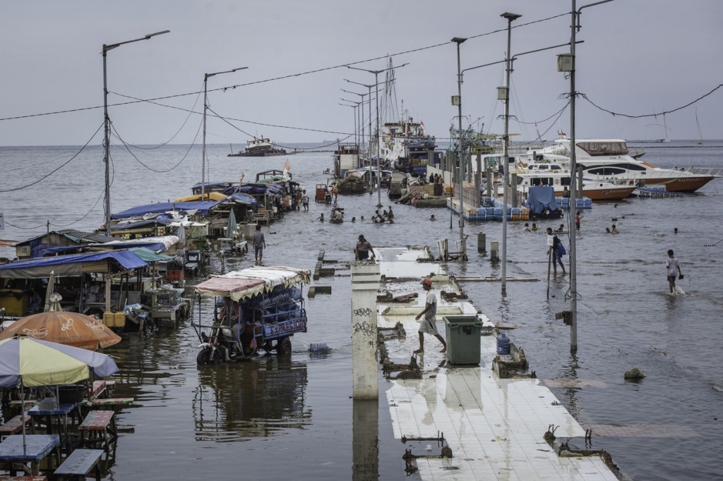 Warga beraktivitas saat banjir rob di Pelabuhan Kali Adem, Muara Angke, Jakarta.
