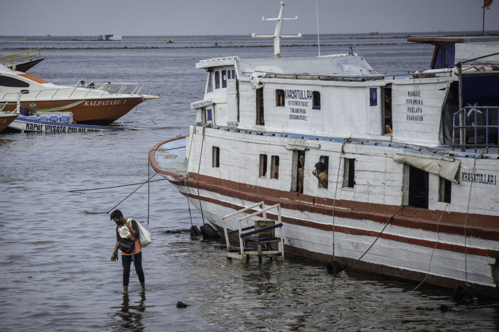 Warga bermain bersama anaknya saat banjir rob di Pelabuhan Kali Adem, Muara Angke, Jakarta.
