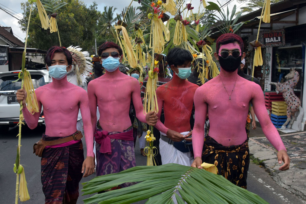 Sejumlah warga yang tubuhnya dihias warna-warni dan menggunakan masker saat berkeliling kampung dalam tradisi Ngerebeg di Desa Tegallalang, Gianyar, Bali.
