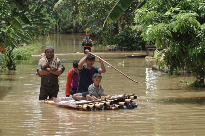 Warga menggunakan rakit darurat untuk melakukan evakuasi dari rumah yang terendam banjir di Desa Gentasari, Kroya, Cilacap, Jawa Tengah, Selasa, 27 Oktober 2020.