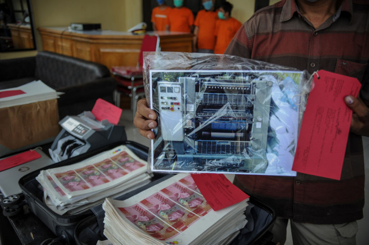 Petugas kepolisian berpakaian sipil menunjukkan barang bukti berupa foto mesin produksi uang palsu pecahan seratus ribu rupiah saat rilis di Polrestabes Bandung, Jawa Barat, Rabu, 28 Oktober 2020.