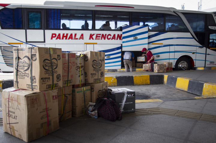 Calon penumpang memasukkan barang bawaan ke bagasi bus di Terminal Terpadu Pulo Gebang, Jakarta.