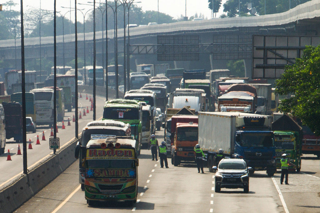 Petugas kepolisan mengatur lalu lintas kendaraan saat pemberlakuan rekayasa lalu lintas di jalan tol Jakarta - Cikampek (Japek) KM 47, Karawang, Jawa Barat. ANTARA Foto/Muhamad Ibnu Chazar 
