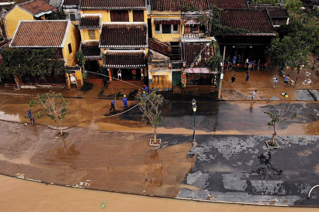 Petugas tengah membersihkan jalanan dari endapan lumpur tebal pasca terjangan topan Molave di Hoi An, Vietnam, Jumat, 30 Oktober 2020.