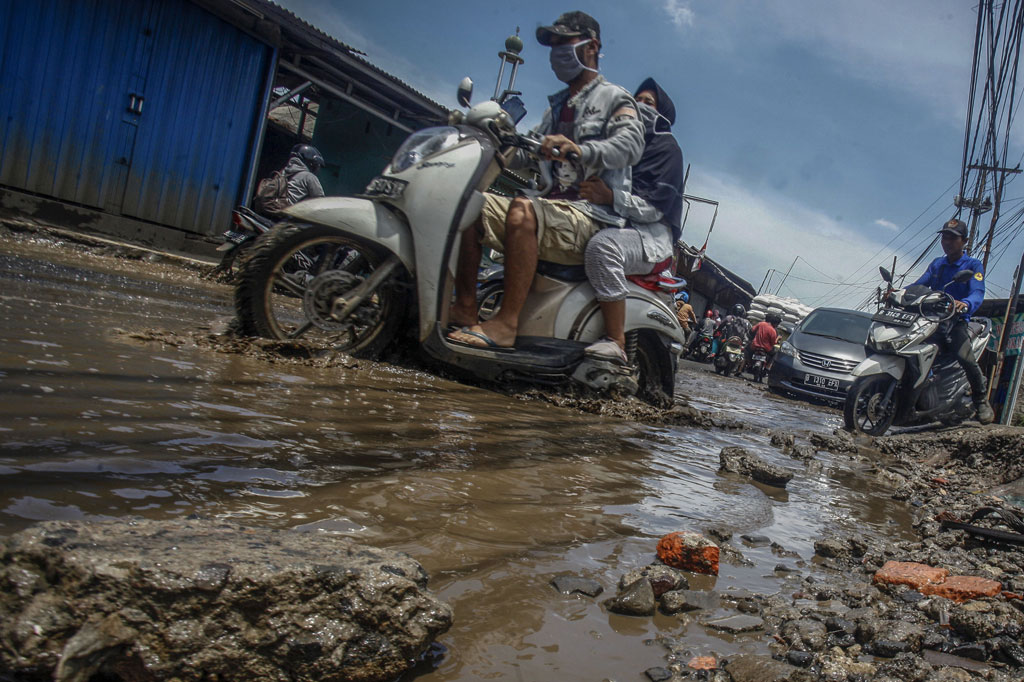 Pengendara memperlambat laju kendaraan saat melintasi jalan yang rusak dan tergenang air di jalan penghubung antara Kabupaten Bogor dan Kota Depok, Pabuaran, Bojong Gede, Kabupaten Bogor, Jawa Barat, Selasa, 3 November 2020.