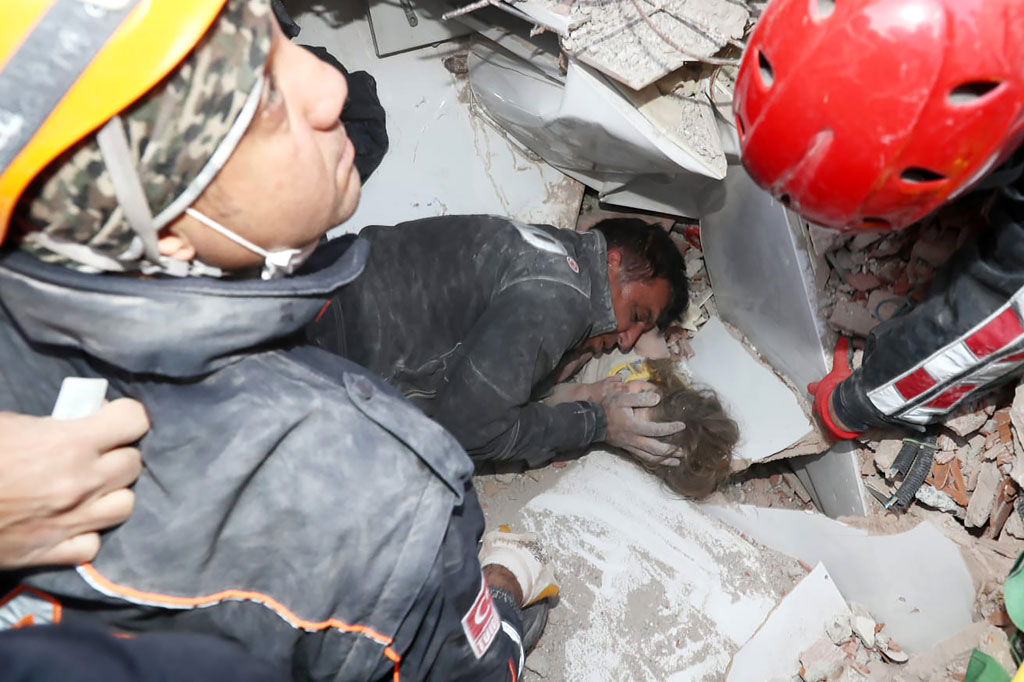 Seorang petugas penyelamat sedang menghibur seorang gadis berusia 3 tahun, Ayda Gezgin, yang terperangkap di reruntuhan bangunan rumahnya pascagempa bumi di kota pelabuhan Aegean Izmir, Turki pada Senin, 3 November 2020.