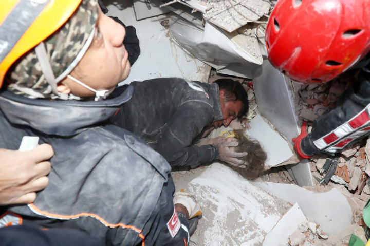 Seorang petugas penyelamat sedang menghibur seorang gadis berusia 3 tahun, Ayda Gezgin, yang terperangkap di reruntuhan bangunan rumahnya pascagempa bumi di kota pelabuhan Aegean Izmir, Turki pada Senin, 3 November 2020.
