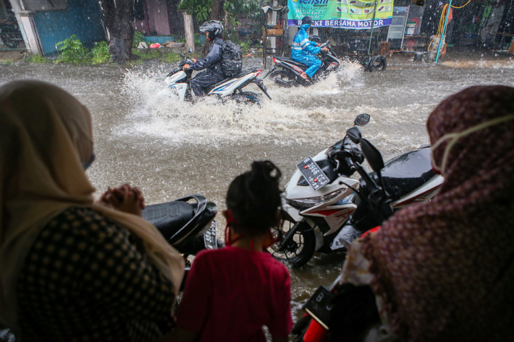 Pengendara melintas di genangan air di Kelapa Dua, Kabupaten Tangerang, Banten.