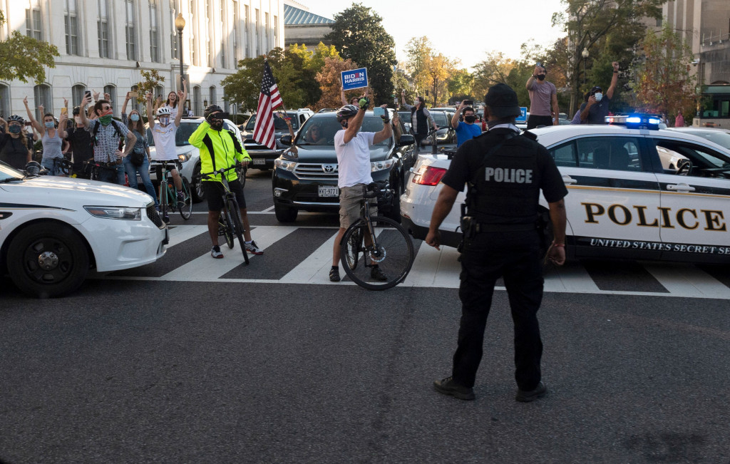 Iring-iringan mobil kepresidenan melaju di dekat Black Lives Matter Plaza, di seberang Gedung Putih, tempat kerumunan besar orang merayakan kekalahan Trump.