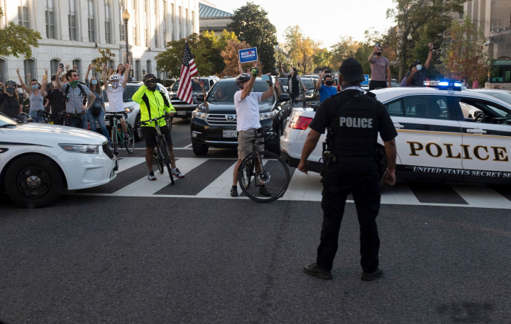 Iring-iringan mobil kepresidenan melaju di dekat Black Lives Matter Plaza, di seberang Gedung Putih, tempat kerumunan besar orang merayakan kekalahan Trump.