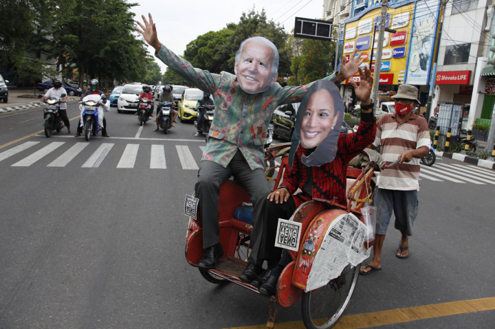 Warga menggunakan topeng berwajah pasangan Presiden Amerika Serikat terpilih Joe Biden (kiri) dan Wakil Presiden Kamala Harris (kanan) di Jalan Slamet Riyadi, Solo, Jawa Tengah.