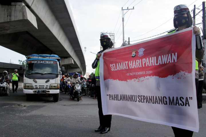 Anggota Ditlantas Polda Sulsel membentangkan spanduk saat mengheningkan cipta di Jalan AP Pettarani, Makassar, Sulawesi Selatan, Selasa, 10 November 2020. Kegiatan tersebut untuk mengajak pengguna jalan berhenti sejenak mengheningkan cipta guna mengenang jasa para pahlawan dalam rangka memperingati Hari Pahlawan. ANTARA FOTO/Arnas Padda