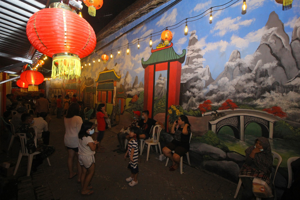 Pengunjung berfoto di depan salah satu mural bernuansa Tionghoa saat peluncuran awal Wisata Kampung Pecinan di Jalan Kapasan Dalam, Surabaya, Jawa Timur.

