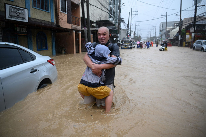 Warga melintasi jalanan yang direndam banjir setelah topan Vamco melanda di Kota Marikina, pinggiran Manila, Filipina, Kamis, 12 November 2020.