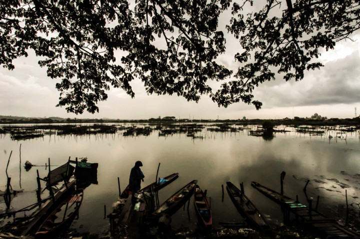 Seorang warga melihat perahu nelayan yang ditambatkan di kawasan waduk yang tercemar limbah mercuri di Lhokseumawe, Aceh.