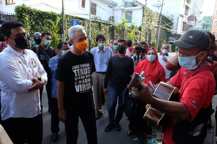 Calon Wali Kota Medan nomor urut dua Bobby Nasution (kiri) didampingi politikus PDI Perjuangan Ganjar Pranowo (kedua kiri) mendengarkan lagu yang dinyanyikan pengamen saat mengunjungi kawasan kota tua Kesawan, di Medan, Sumatera Utara.