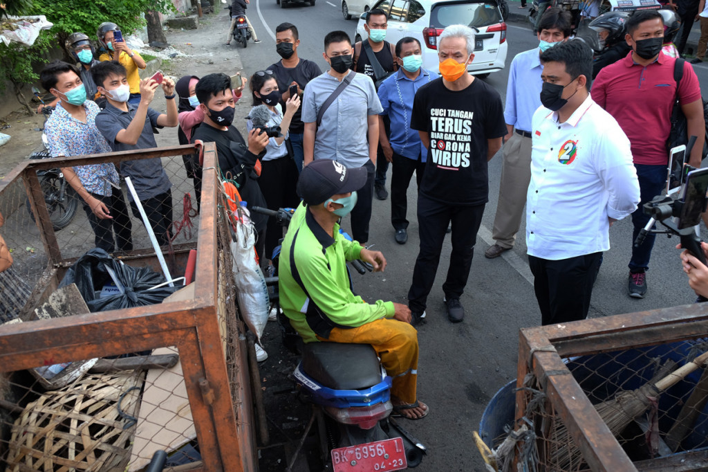 Calon Wali Kota Medan nomor urut dua Bobby Nasution (kedua kanan) didampingi politikus PDI Perjuangan Ganjar Pranowo (ketiga kanan) berbincang dengan petugas kebersihan saat mengunjungi kawasan kota tua Kesawan, di Medan, Sumatera Utara.