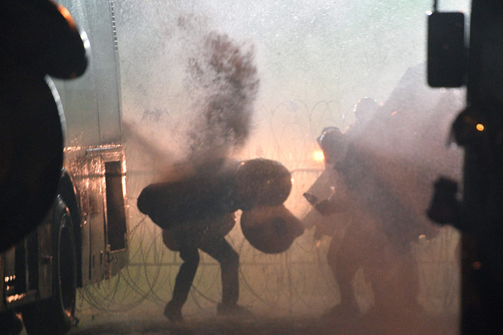 Saat bentrok dengan polisi sejumlah demonstran terlihat menggunakan bebek karet sebagai tameng untuk melindungi diri dari meriam air. AFP Photo/Mladen Antonov