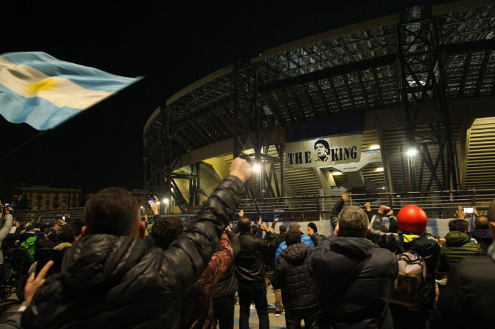 Penggemar memberi penghormatan terakhir untuk mendiang Diego Maradona di luar Stadiom San Paolo, Naples, Rabu, 25 November 2020. Napoli dibela Maradona pada 1984-1991 dan menjuarai Serie A 1986/87 dan 1989/90. Demi menghormati jasa-jasa sang mega bintang kepada klub tersebut, nama Maradona akan ditambahkan ke nama stadion Napoli.