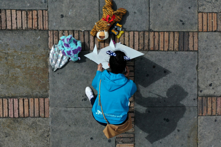Seorang aktivis meletakkan boneka dan pesan di alun-alun Bolivar dalam demonstrasi menentang pelecehan anak di Bogota, Kolombia.