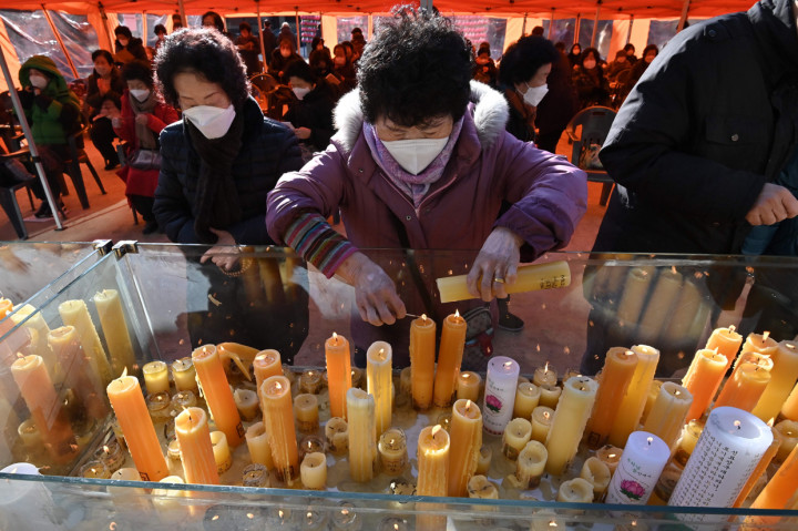 Para orang tua meletakkan lilin selama kebaktian khusus untuk mendoakan keberhasilan anak-anak mereka dalam ujian masuk perguruan tinggi di Kuil Buddha Jogyesa, Seoul Korea Selatan, Kamis, 3 Desember 2020. 