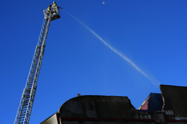 Petugas pemadam kebakaran melakukan pembasahan di lokasi kebakaran di gudang tempat yang ditempati sekitar 200 migran di Badalona, ??dekat Barcelona, Kamis, 10 Desember 2020.