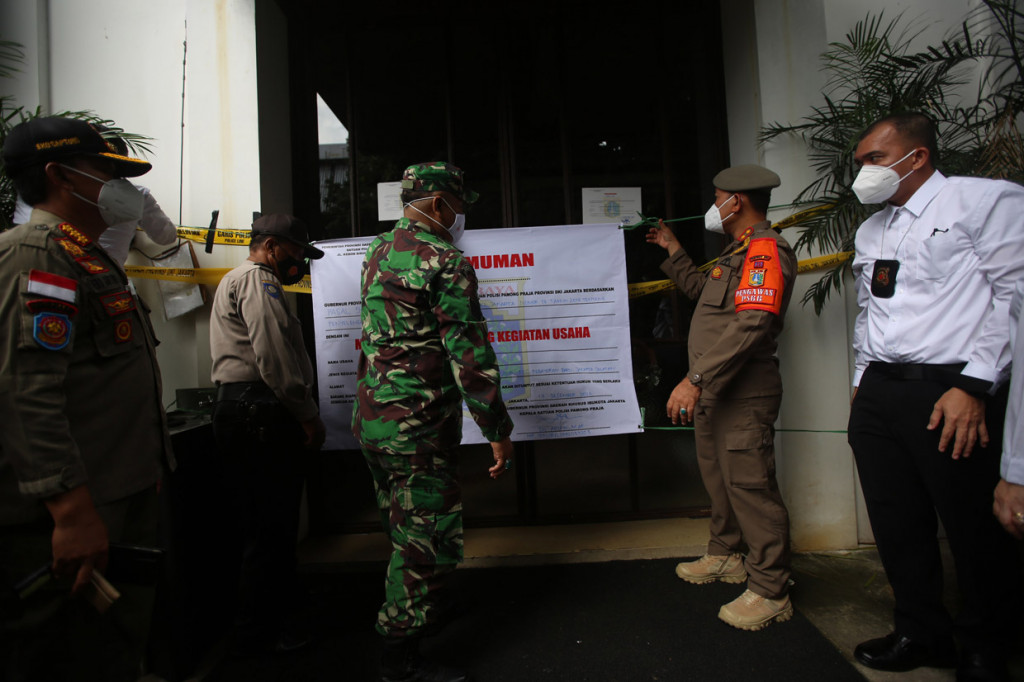 Kasatpol PP DKI Jakarta Arifin (kedua kanan) memasang segel permanen di Kilo Kitchen, Jakarta.