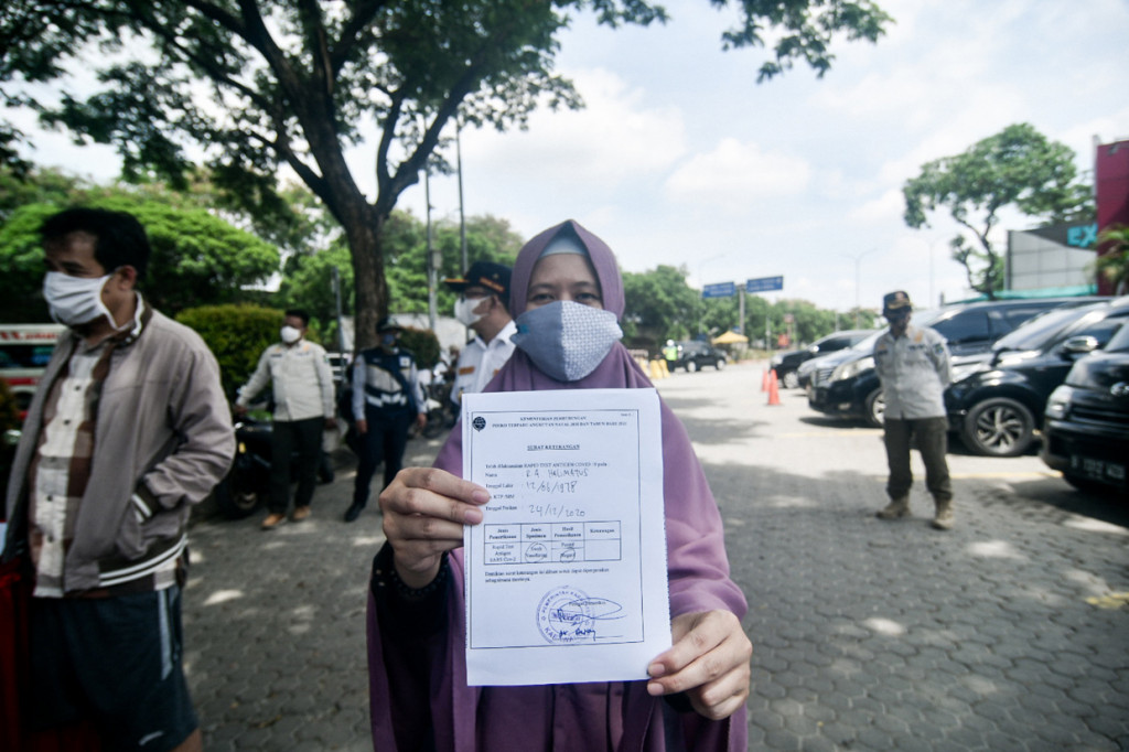 Warga menunjukan surat hasil Rapid Test Antigen yang yang dilakukan di Rest Area KM 57, Karawang, Jawa Barat.