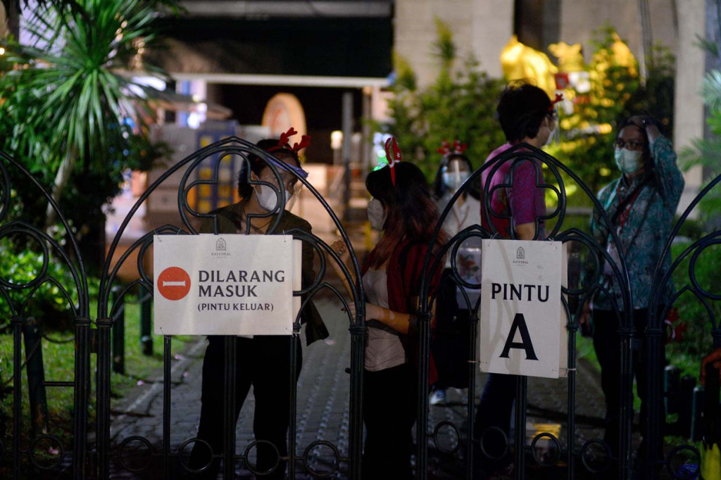 Orang Muda Katholik (OMK) membantu mengkoordinir para jemaat yang hadir dalam malam Misa Natal di Gereja Katedral, Jakarta.