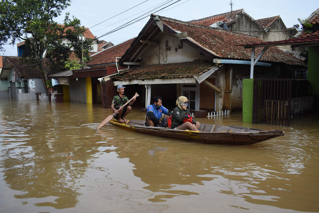Warga menggunakan perahu melintasi banjir yang merendam wilayah Dayeuhkolot, Kabupaten Bandung, Jawa Barat, Jumat, 25 Desember 2020.