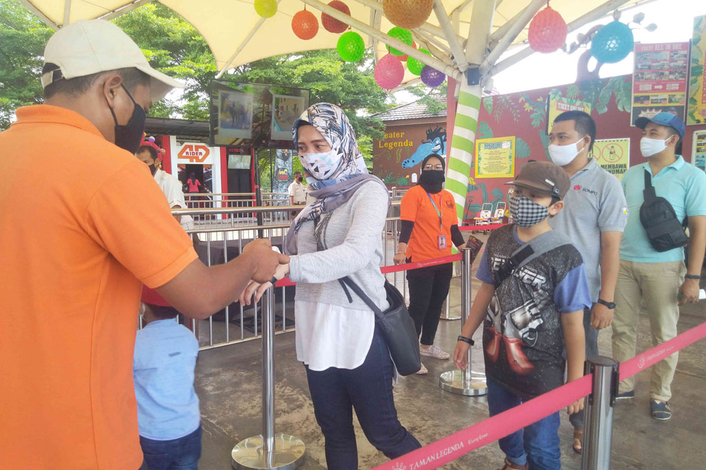 Pengunjung dicek suhu tubuhnya oleh petugas sebelum memasuki kawasan Taman Mini Indonesia Indah (TMII), Jakarta Timur, Sabtu, 26 Desember 2020.