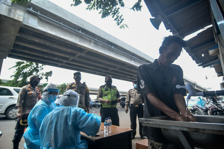 Petugas kesehatan melakukan rapid test pada warga yang terjaring razia protokol kesehatan di Jalan Raya Kalimalang, Bekasi, Jawa Barat.
