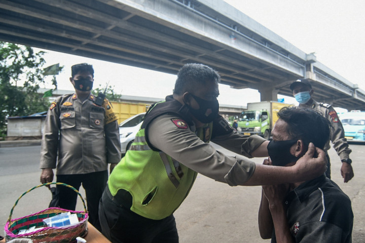 Petugas kepolisian memberikan masker pada warga yang terjaring razia protokol kesehatan di Jalan Raya Kalimalang, Bekasi, Jawa Barat.