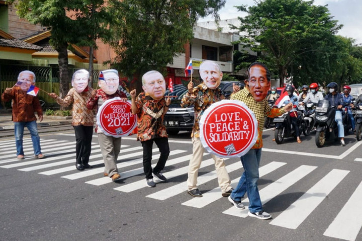 Anggota Republik Aeng Aeng memakai topeng sejumlah pemimpin dunia sambil membawa poster ucapan sambut Tahun Baru 2021 di kawasan Ngarsopuro, Solo, Jawa Tengah, Kamis, 31 Desember 2020. 
