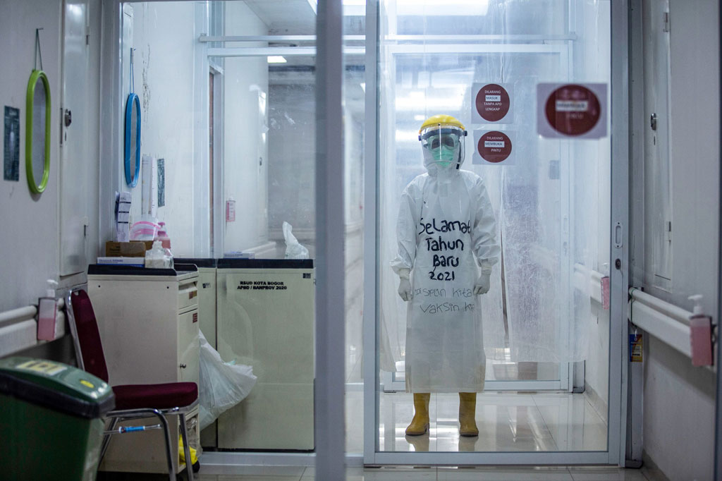 Petugas tersebut mengenakan pakaian alat pelindung diri (APD) yang diberi tulisan 'Selamat Tahun Baru 2021, Disiplin Kita Vaksin Kita'.