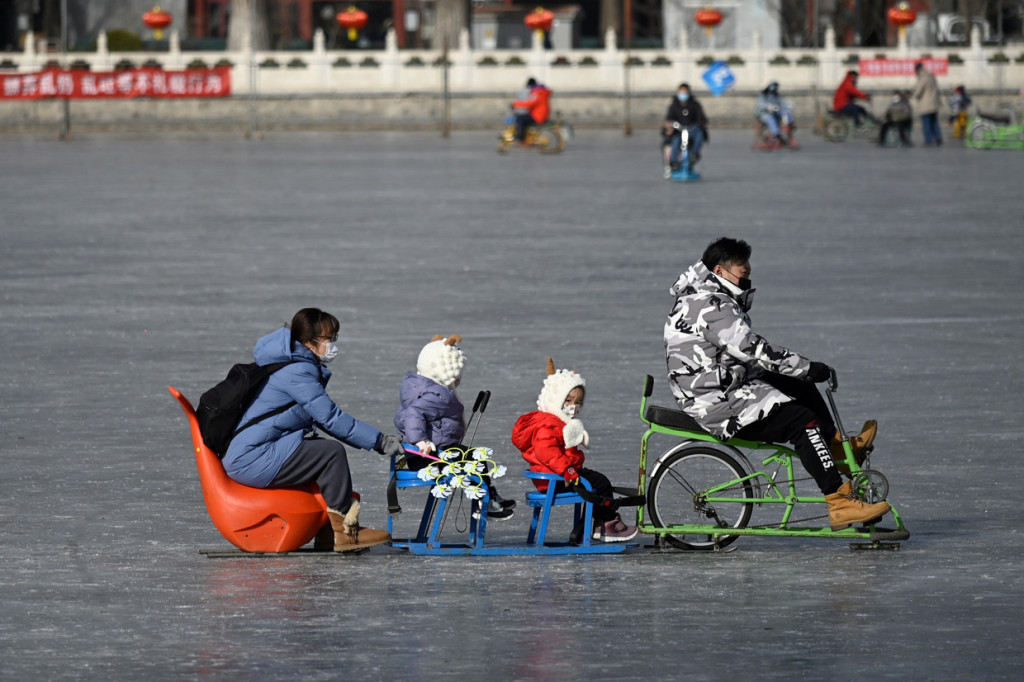 Sebuah keluarga menggunakan kereta luncur di danau beku di Beijing, Selasa, 12 Januari 2021.