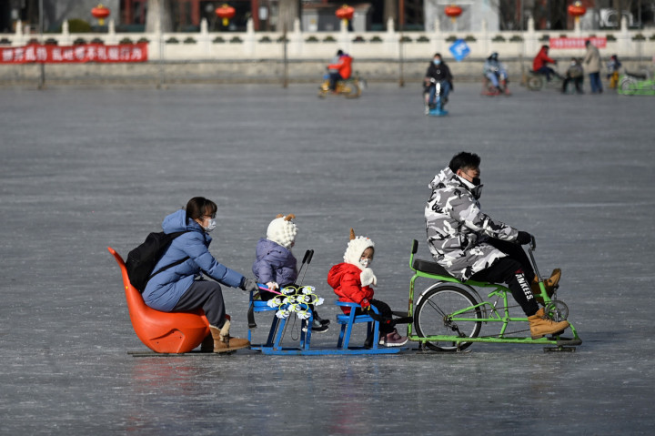 Sebuah keluarga menggunakan kereta luncur di danau beku di Beijing, Selasa, 12 Januari 2021.
