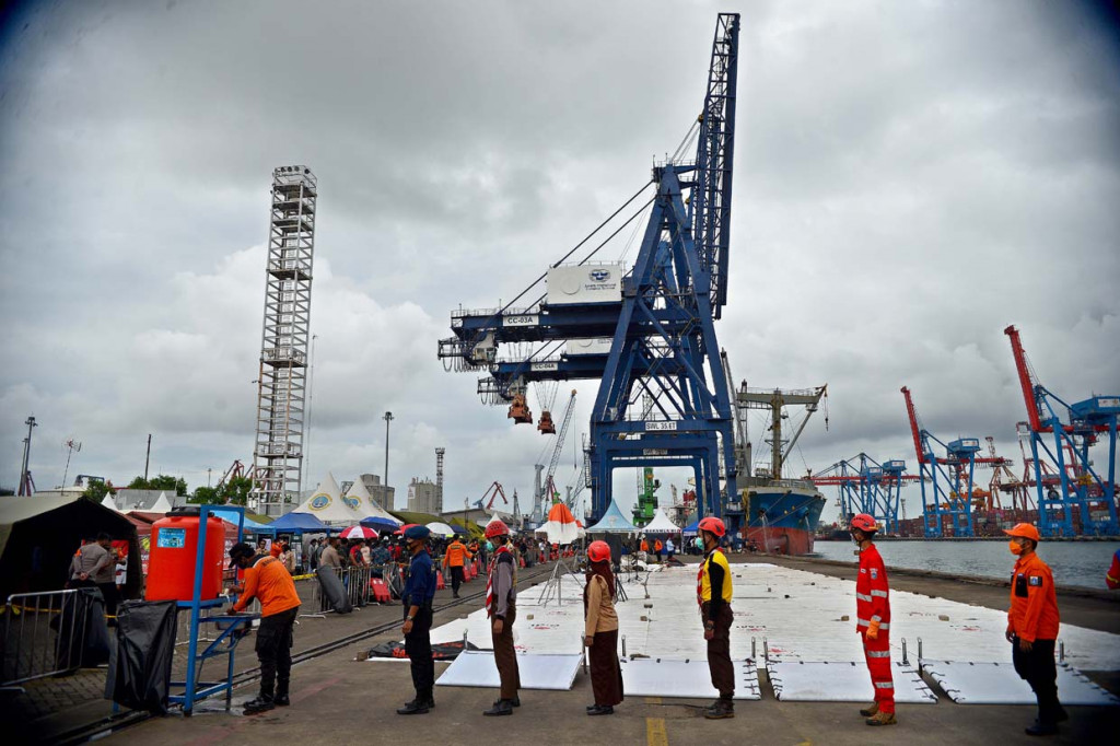 Petugas mencuci tangan usai menata serpihan badan pesawat Sriwijaya Air S-J182 di Jakarta International Container Terminal (JICT), Tanjung Priok, Jakarta.