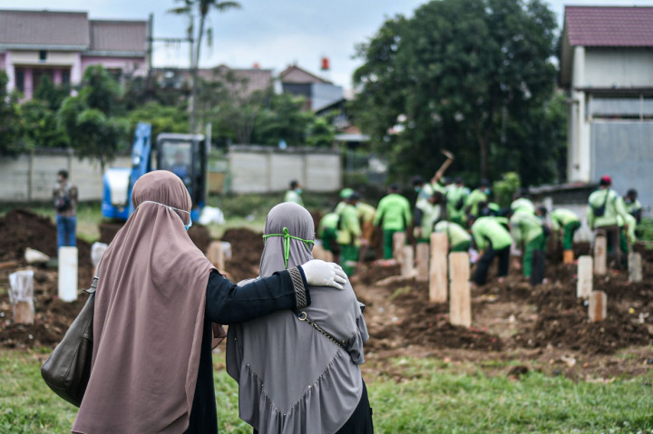 Warga menyaksikan prosesi pemakaman keluarganya yang meninggal akibat Covid-19 di TPU Srengseng Sawah, Jakarta.