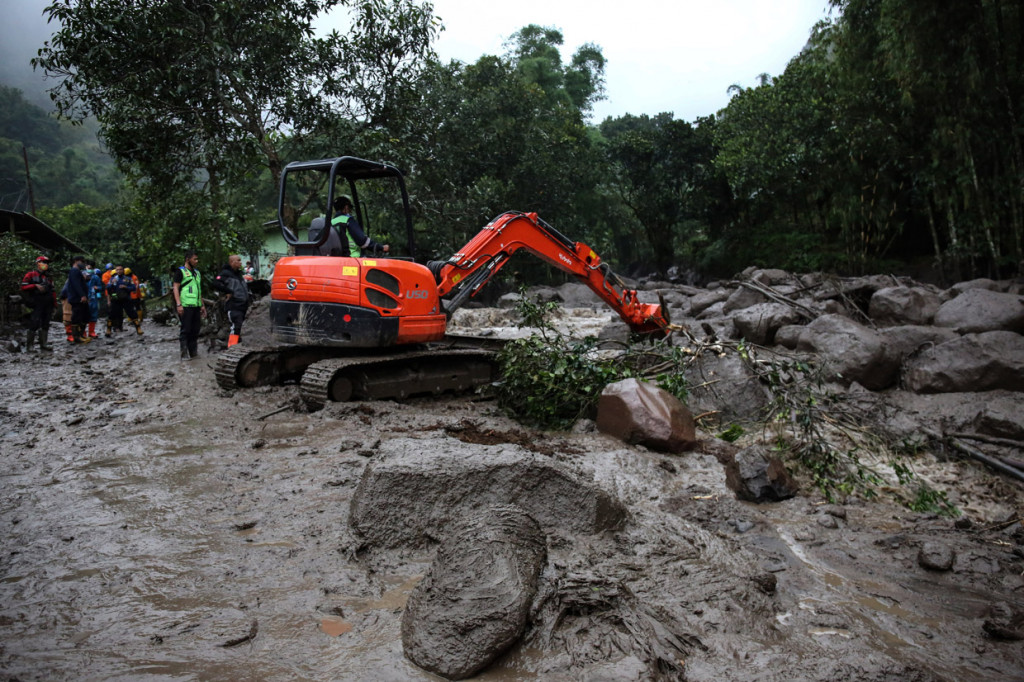 Eskavator memindahkan batu untuk membuka jalan aliran air pascabanjir bandang yang melanda Kampung Gunung Mas, Tugu Selatan, Cisarua, Kabupaten Bogor, Jawa Barat.