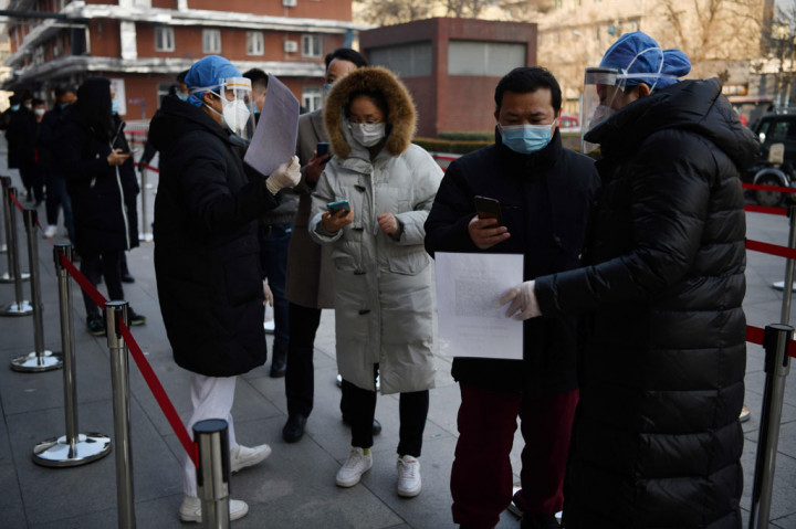 Warga memindai kode QR untuk menampilkan status kesehatan mereka saat berbaris untuk melakukan tes covid-19 di Beijing, Tiongkok.