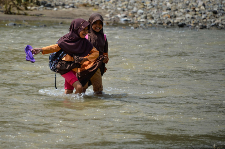 Pasalnya mereka terpaksa menyeberangi sungai yang lumayan lebar dengan arus deras. Mereka terpaksa menyeberangi sungai jembatan gantung di desa tersebut putus sejak 2004 silam, sementara jembatan pengganti yang dibangun pada 2008 hingga kini belum selesai pengerjaannya.
