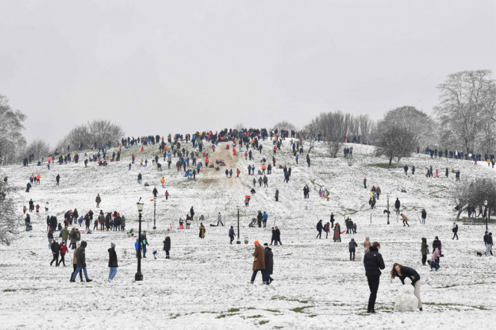 Orang-orang menikmati salju di Primrose Hill saat London mengalami hujan salju yang jarang terjadi pada Minggu, 24 Januari 2021.