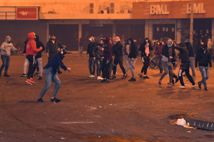 Pengunjuk rasa antipemerintah melemparkan batu ke kompleks Kantor Gubernur Lebanon Utara, di kota pelabuhan Tripoli, Lebanon, Selasa, 26 Januari 2021, malam waktu setempat.