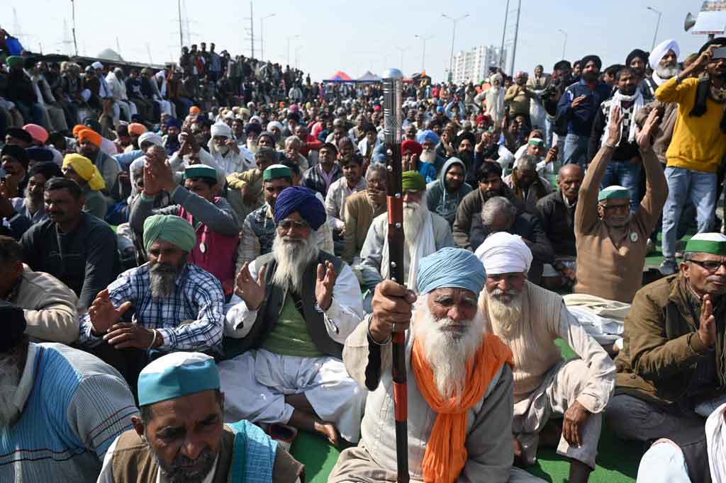 Para petani duduk di jalan raya yang diblokade saat mereka mengambil bagian dalam unjuk rasa memprotes undang undang pertanian baru, di perbatasan negara bagian Delhi-Uttar Pradesh di Ghazipur, India pada Jumat, 30 Januari 2021.