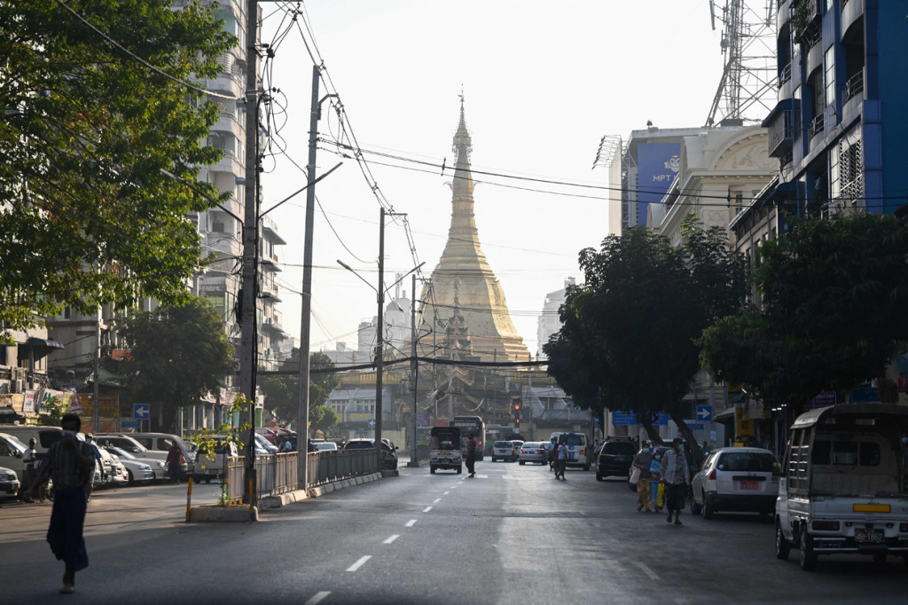 Orang-orang berjalan di sebelah Pagoda Shwedagon di jalan kosong di Yangon, Myanmar.